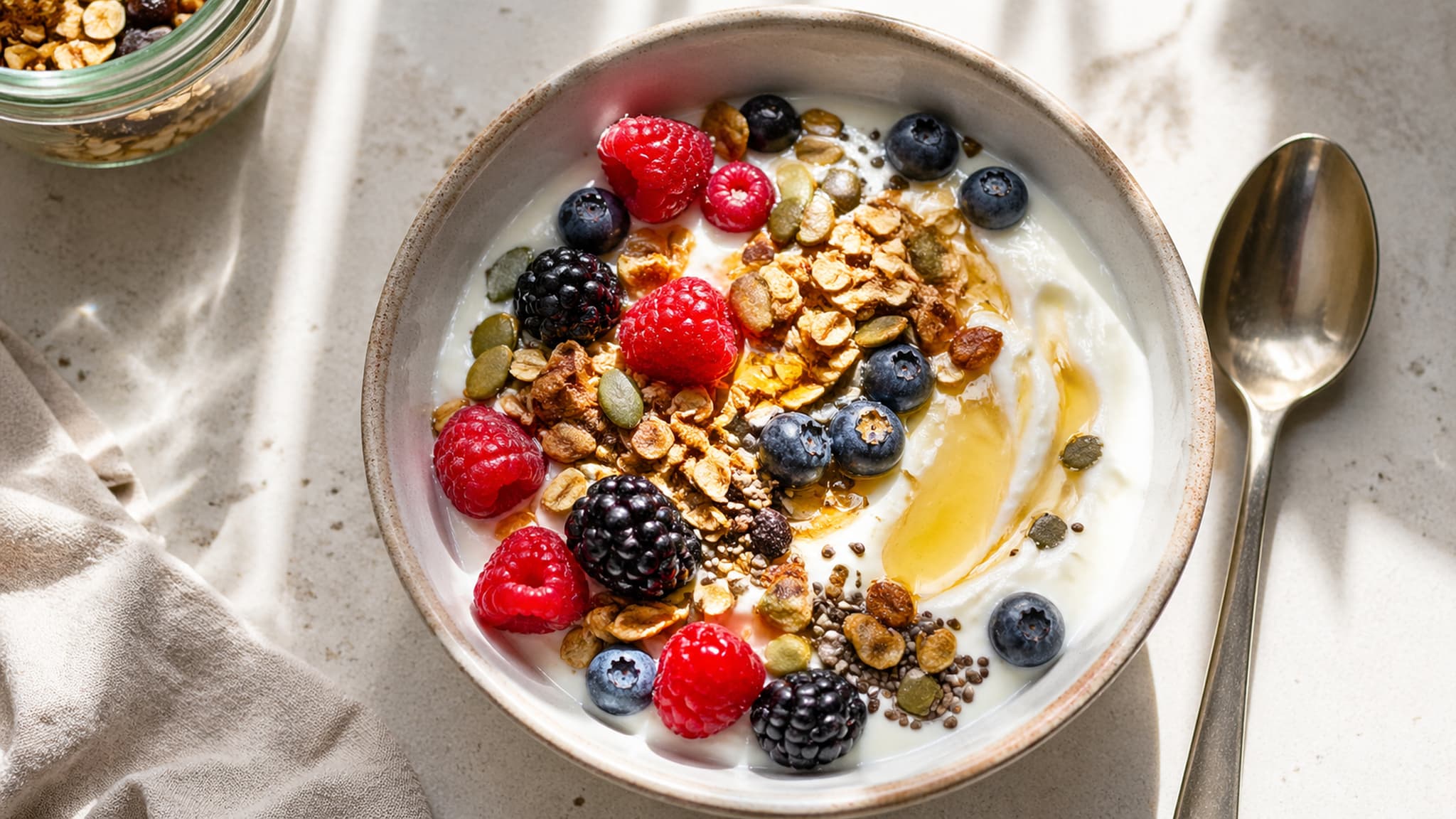 A beautiful yoghurt bowl topped with berries, granola, and seeds
