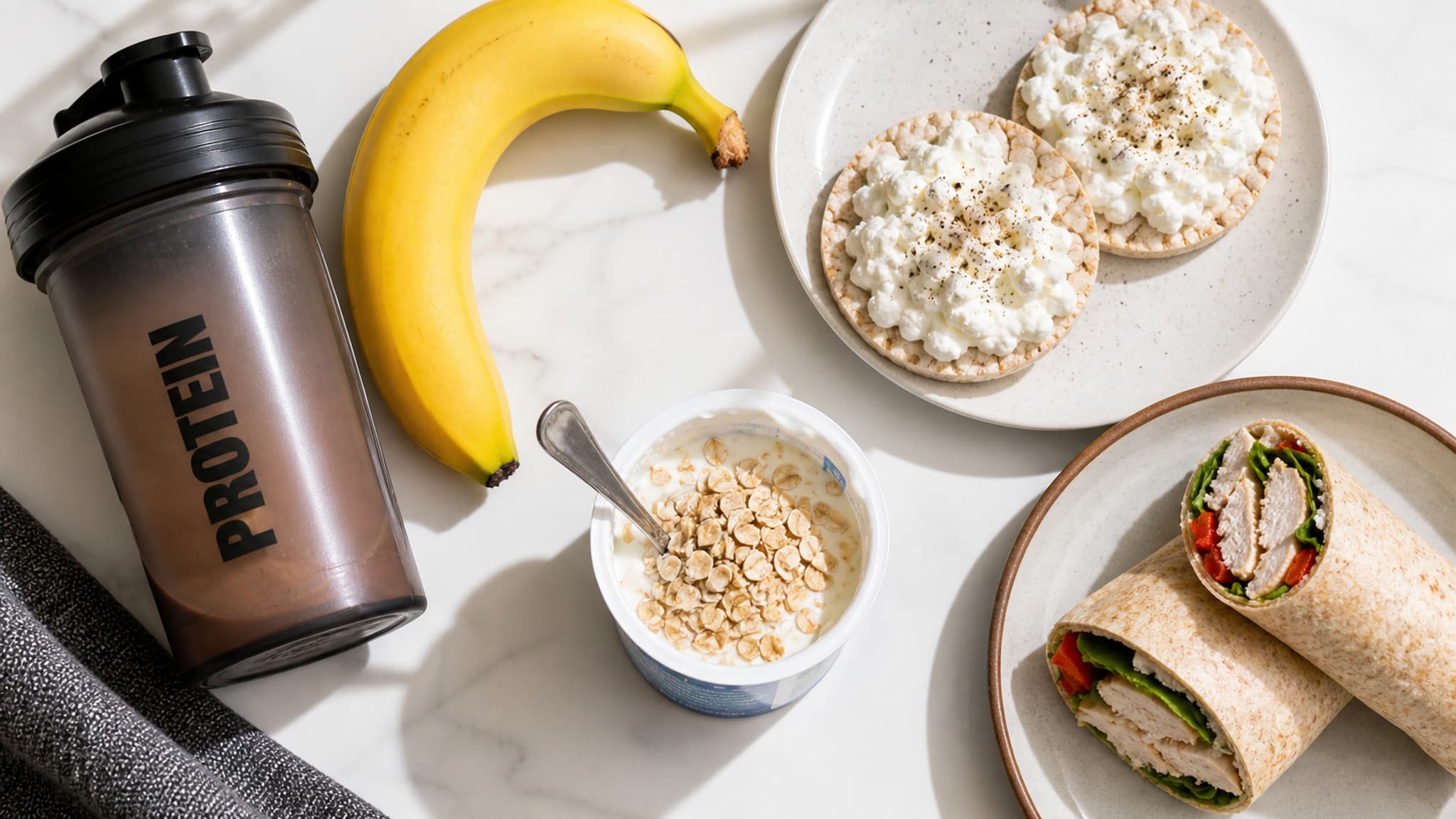 Practical pre-workout snack options — a banana, rice cakes, Greek yoghurt, and a protein shaker displayed as simple and effective pre-training fuel