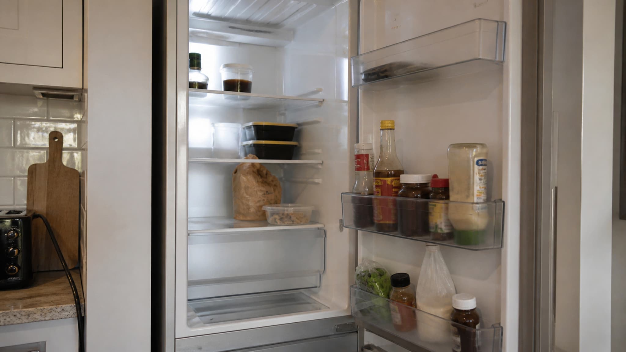 An open refrigerator that is poorly stocked with few fresh food options — illustrating how a poorly planned shop makes good nutrition impossible regardless of motivation