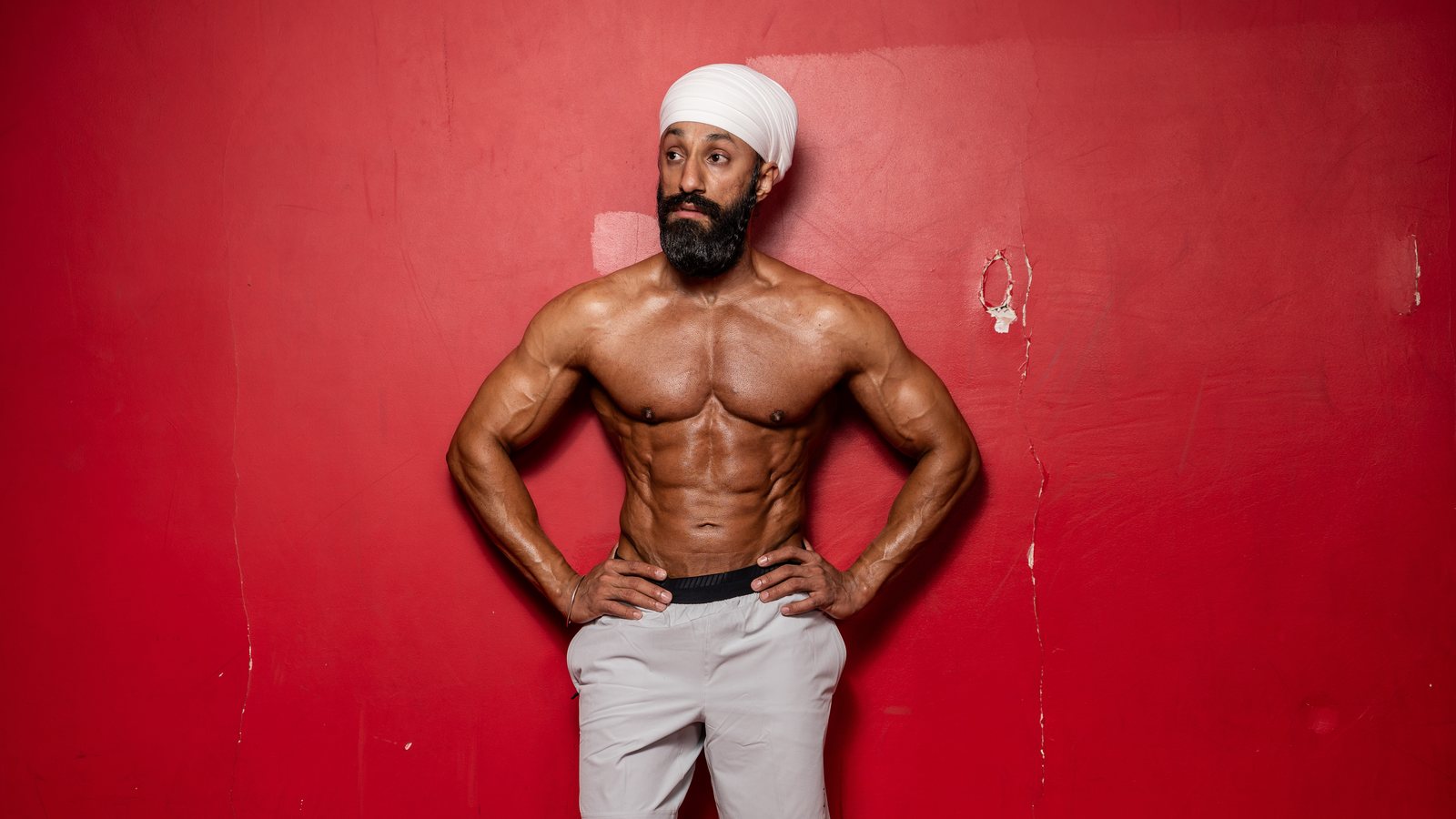 A lean, muscular physique against a red wall