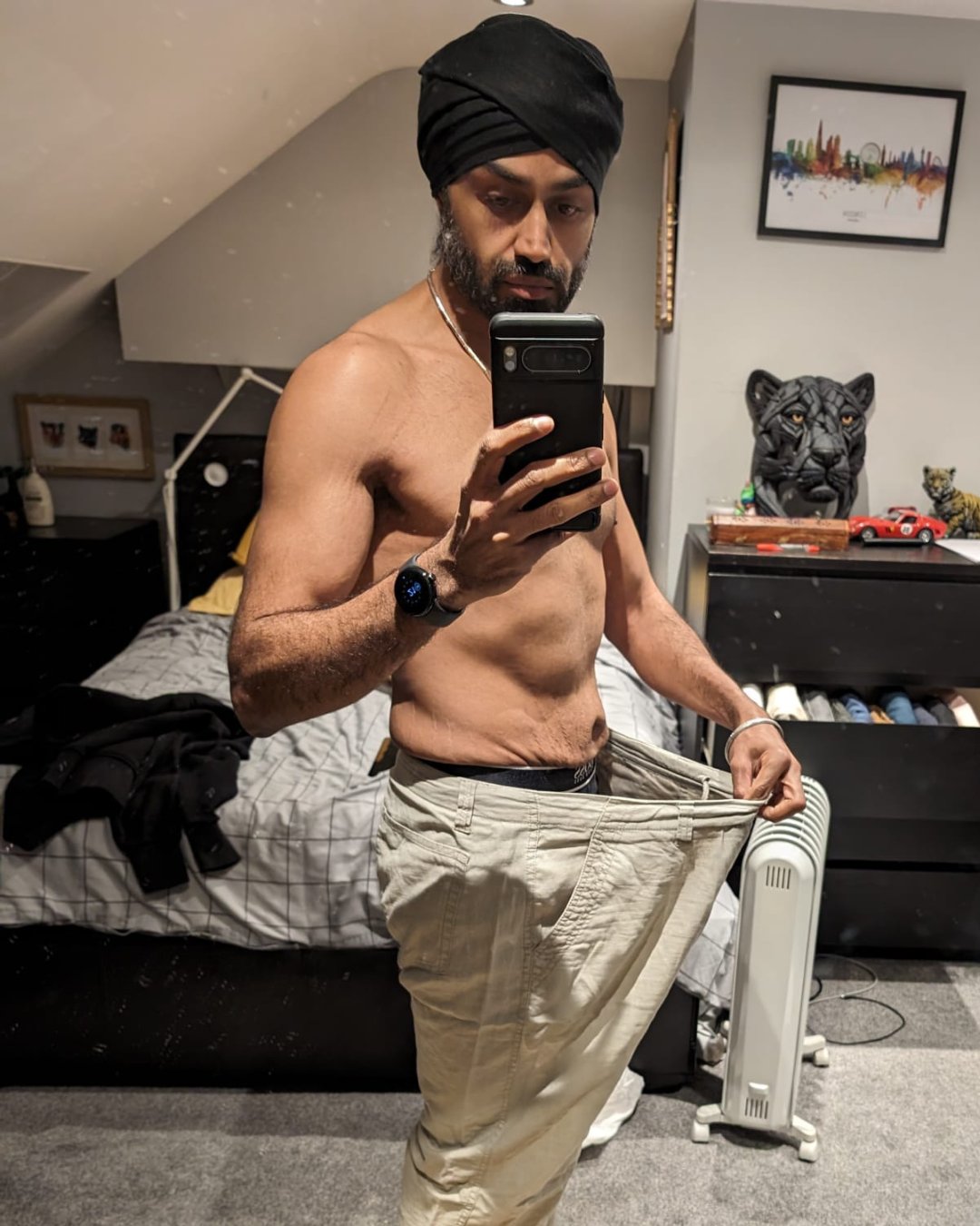 Brinderjit holding out his old oversized trousers after losing the weight
